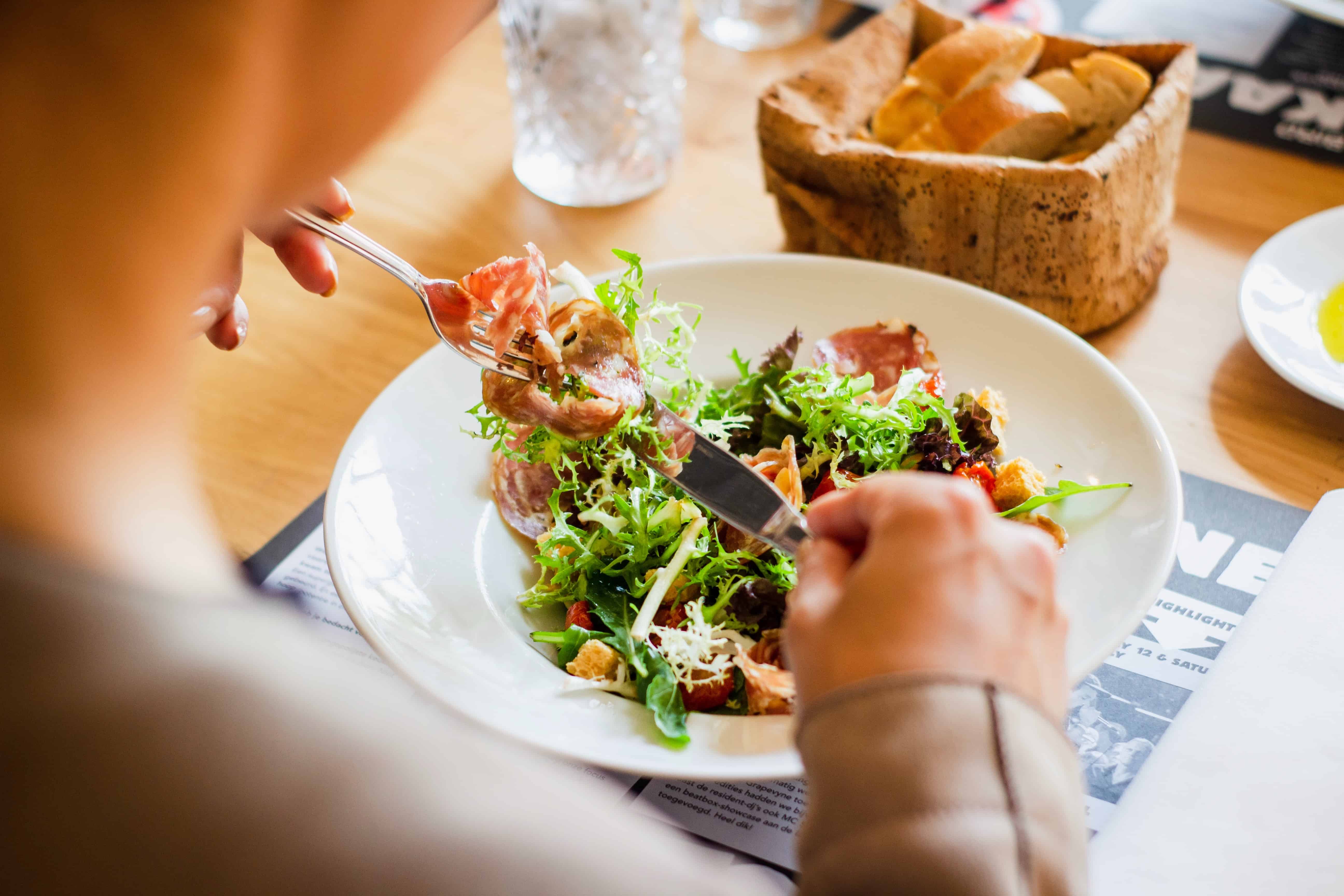 a person eats a healthy looking salad at the table