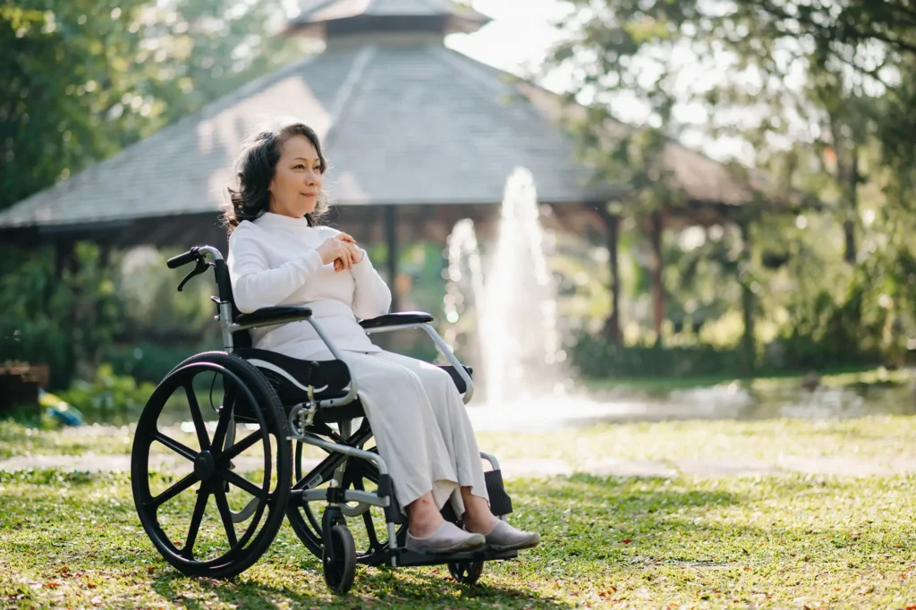 pensive woman sitting in wheelchair outside near fountain in the spring
