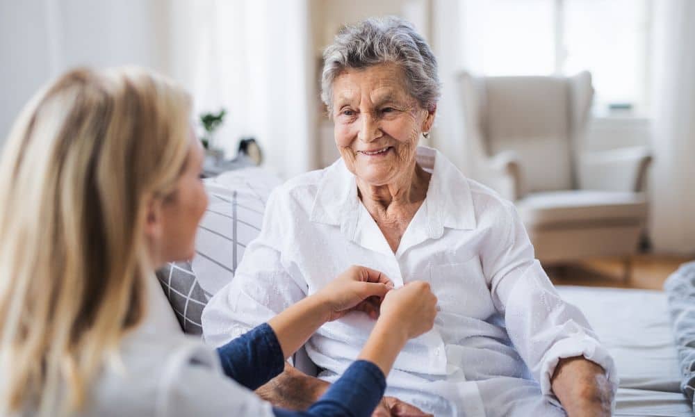 a caregiver helps her client dress up