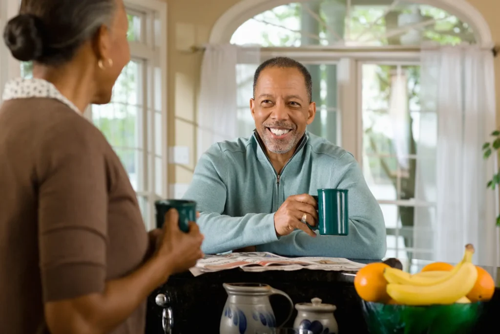 two seniors in the kitchen drinking coffee together