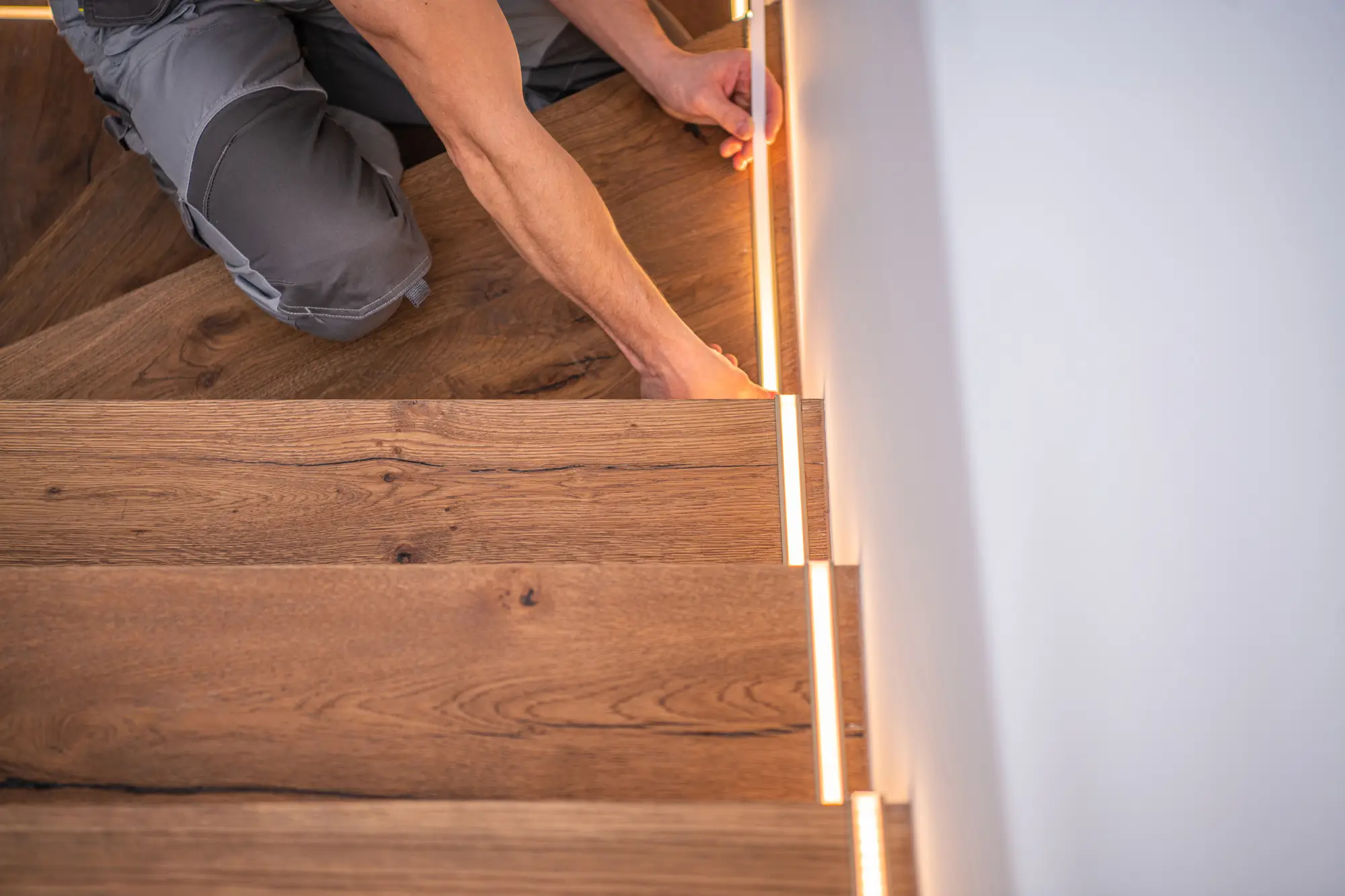 man adding lighting strips to edges of stairs