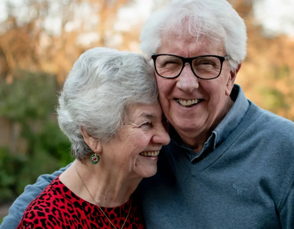 elderly couple smile into the camera