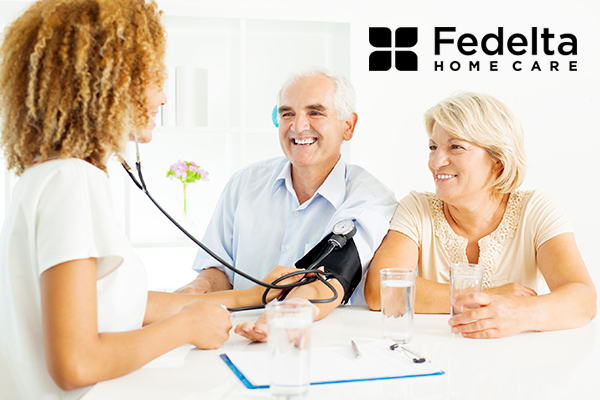 a nurse takes the blood pressure of a senior man in their home