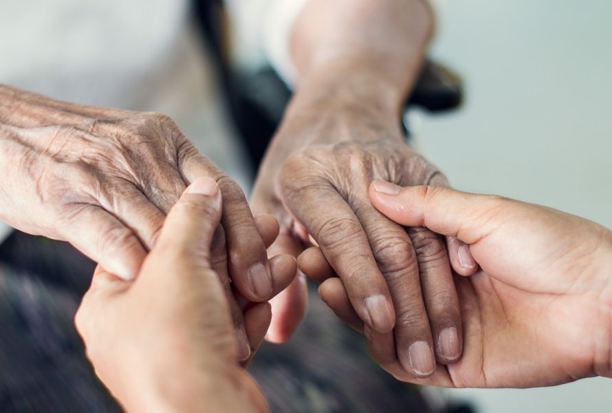 a close up photo of an elderly person holding hands with a caretaker