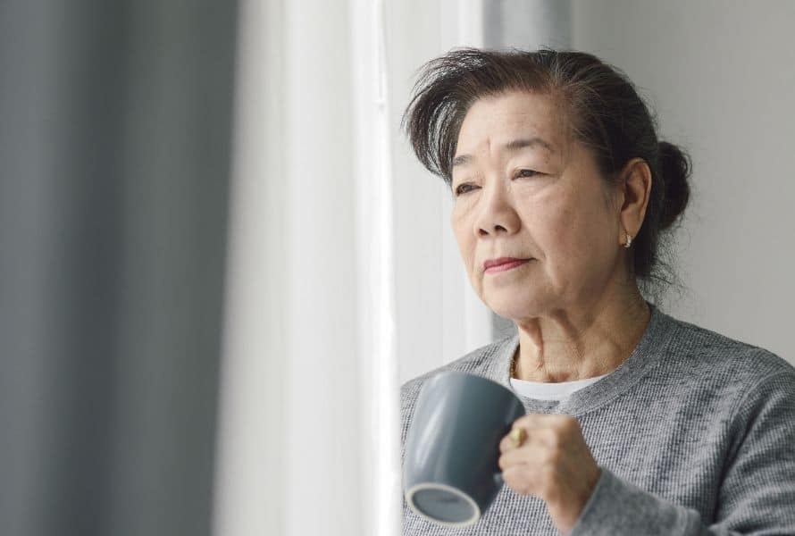 an elderly lady looks outside her window