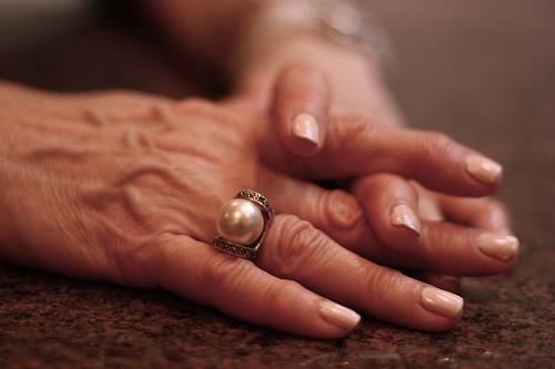 a senior holds their hands together on the table