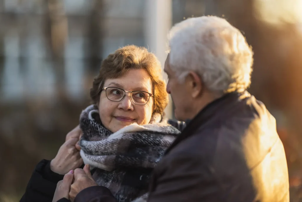 a senior couple smiles at one another during sunset