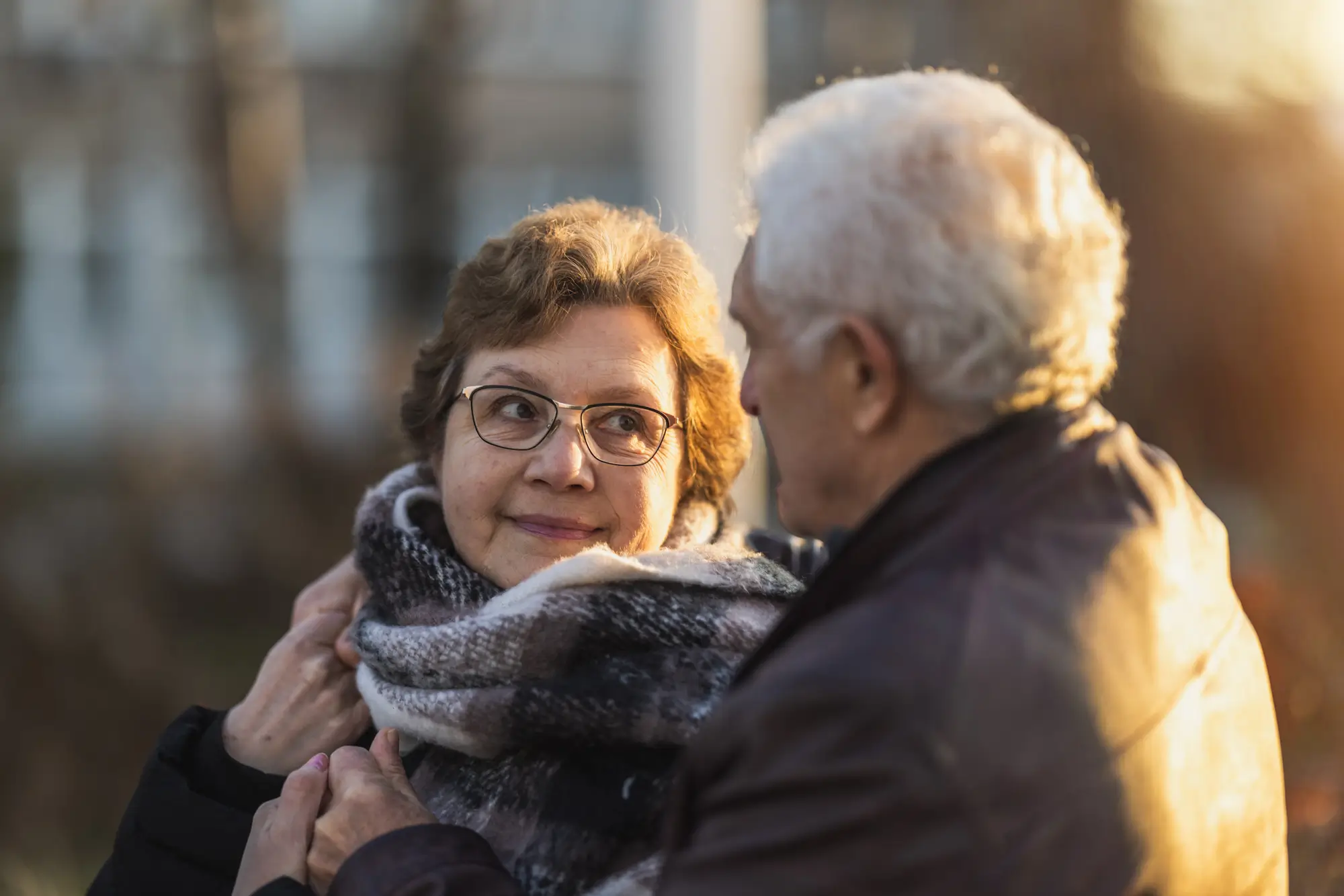 a senior couple smiles at one another during sunset