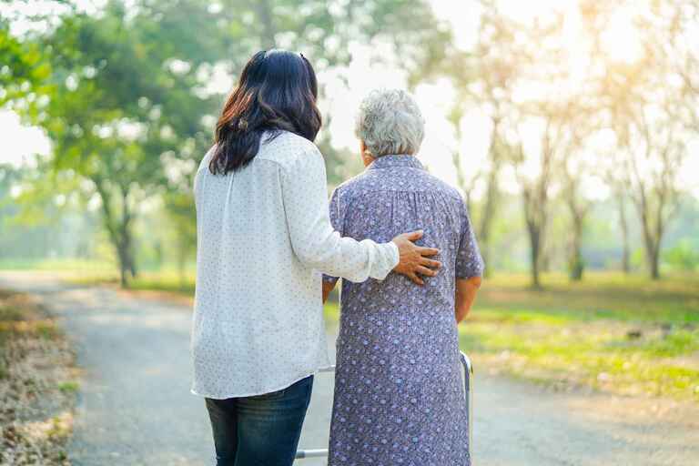 a caregiver and an elderly women go on a walk in the sunshine