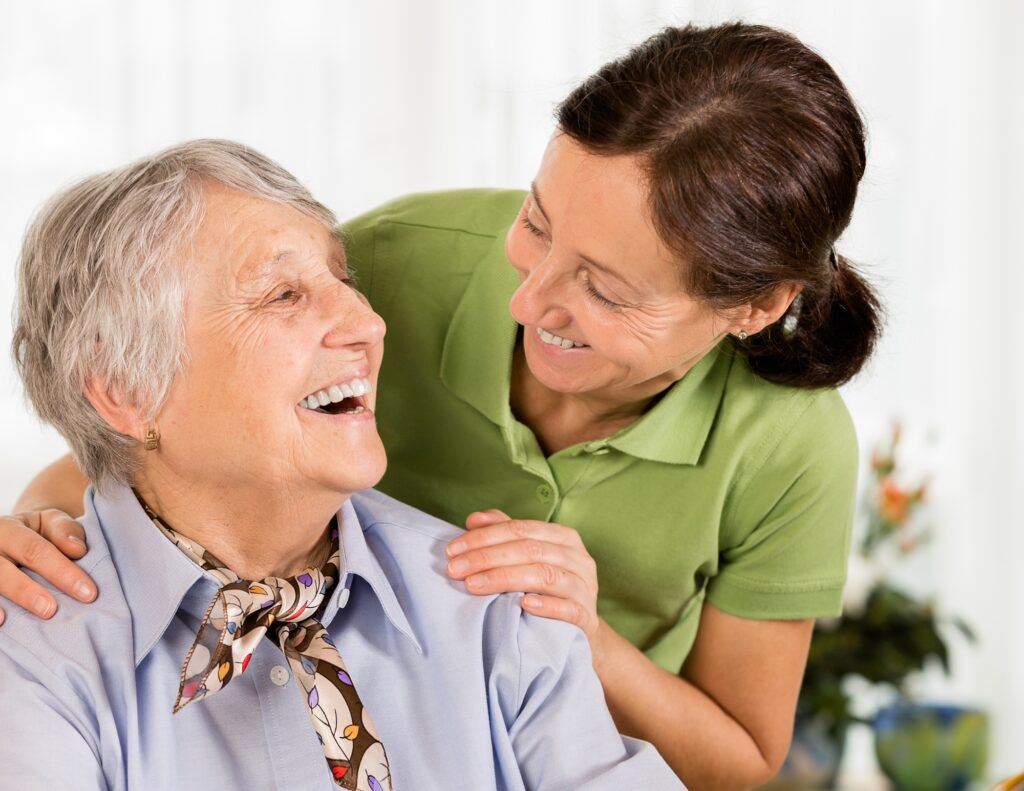 an elderly women smiles with their caregiver