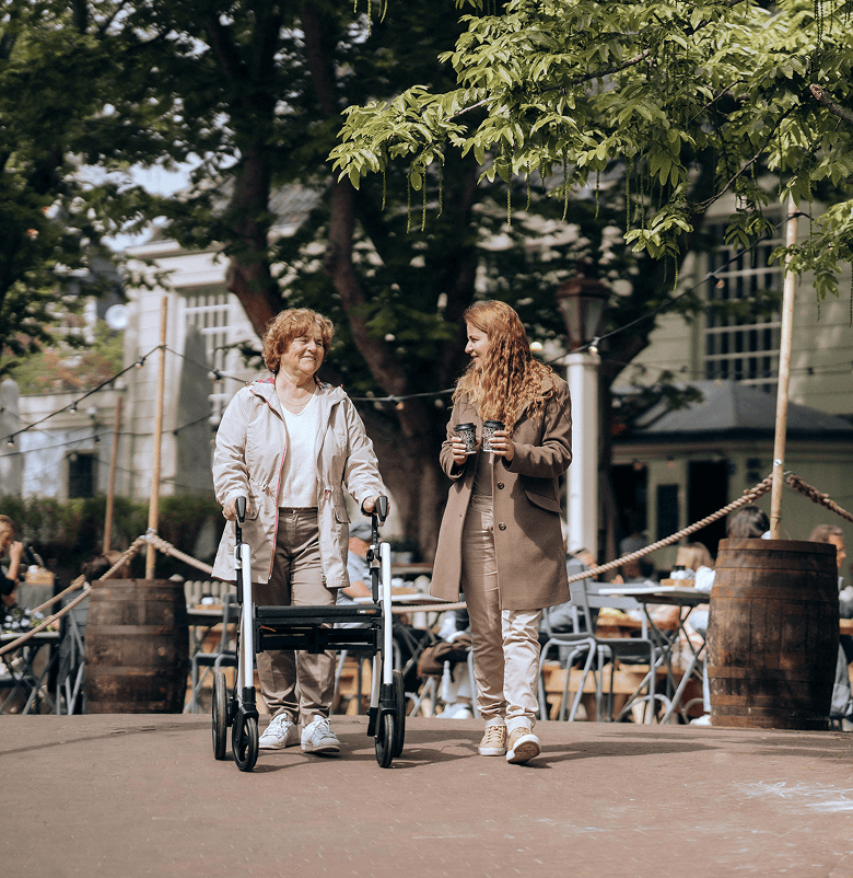 middle aged woman with walker strolls through town square with younger woman
