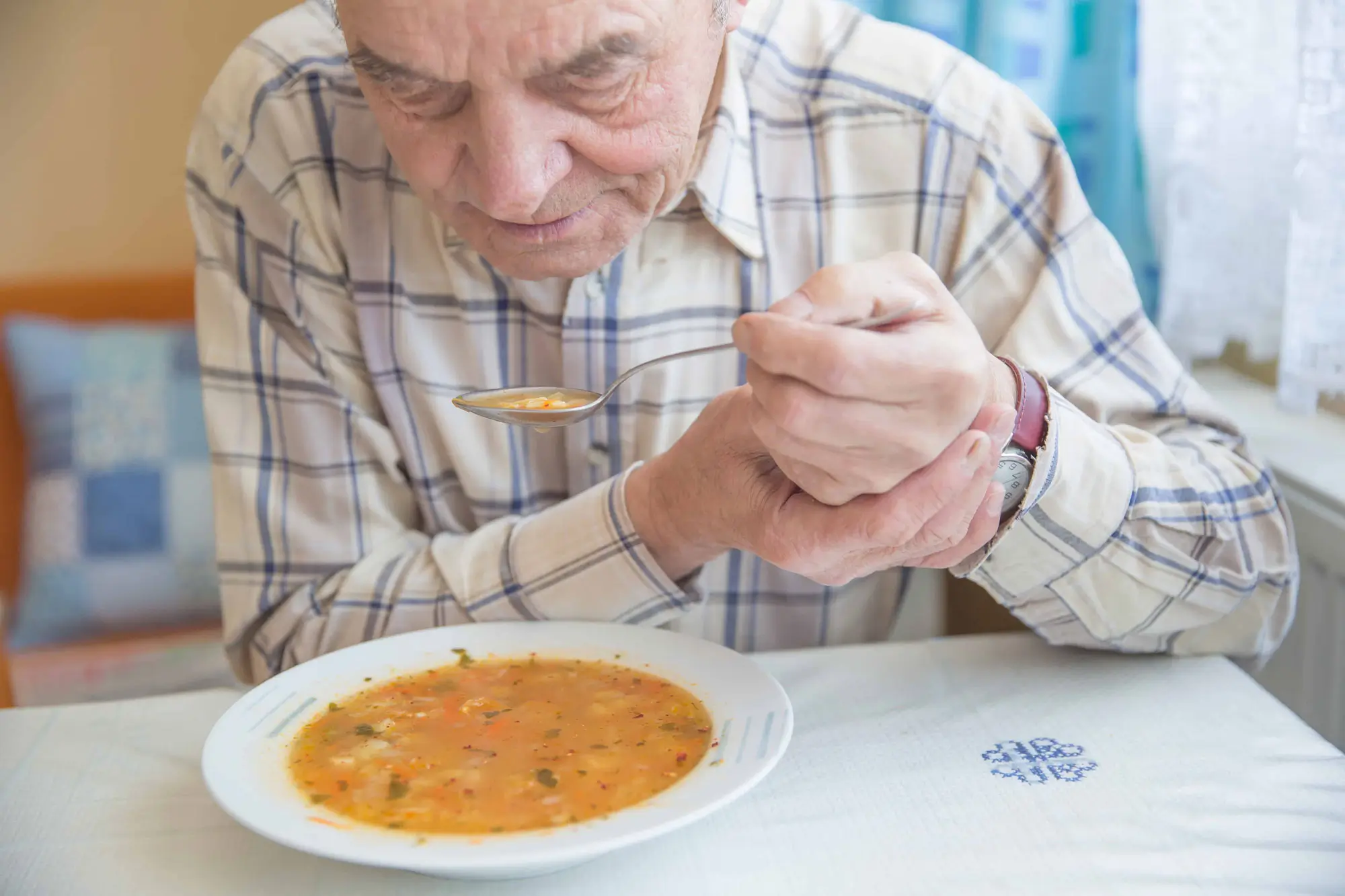 an elderly man eats soup slowly