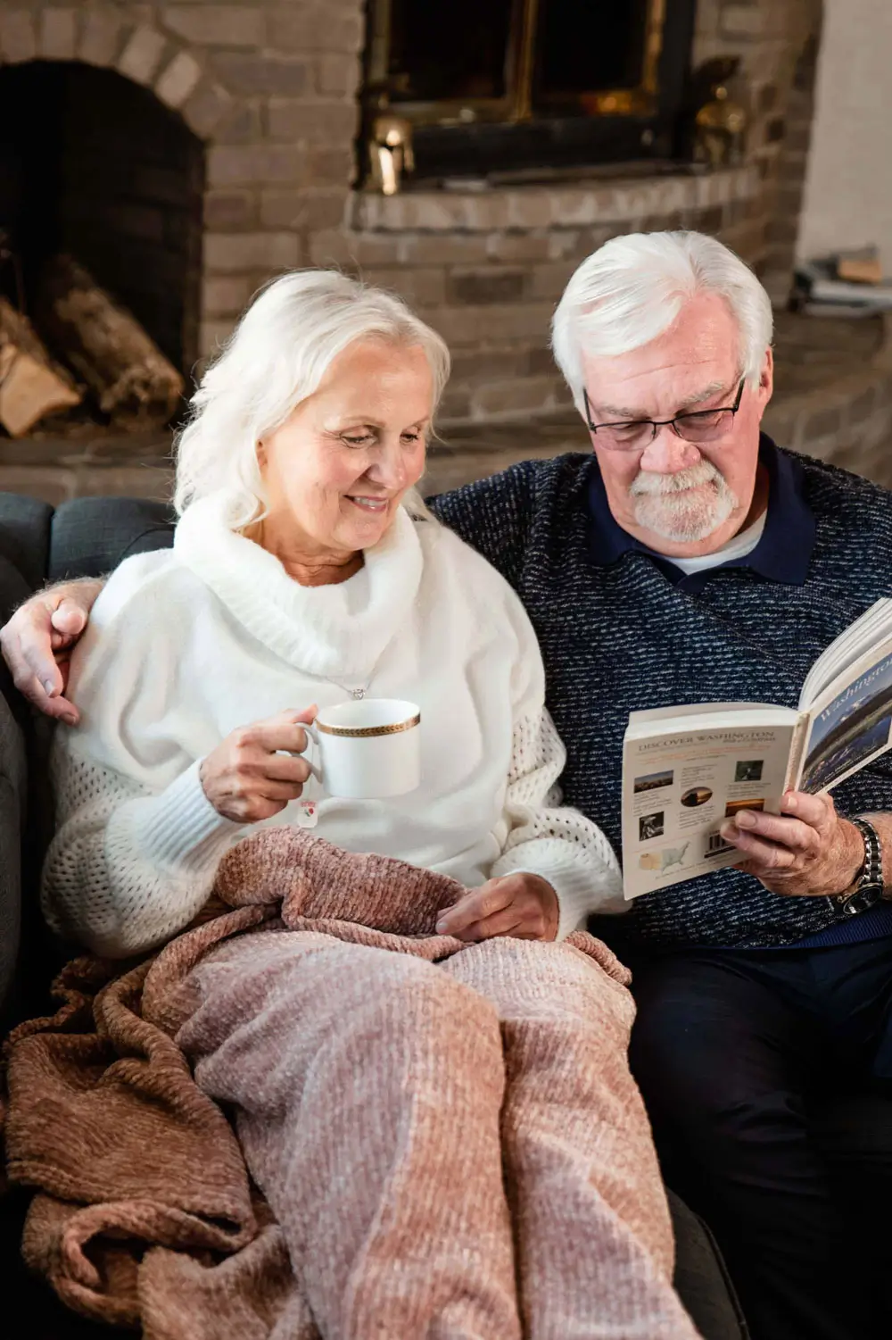 seniors together reading a book on the couch